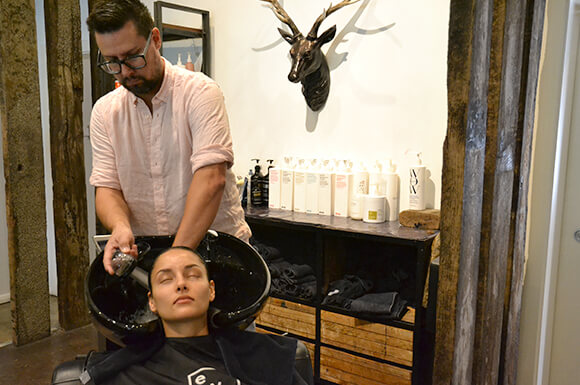 Client having hair washed in basin by hairdresser